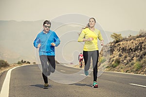 Attractive sport couple man and woman running together on asphalt road mountain landscape