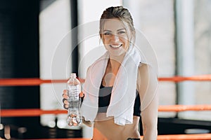 Attractive sport girl smiling and drinking water while standing in fitness class