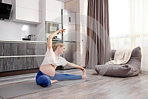 attractive sportive mom-to-be stretching legs during workout at home