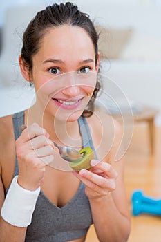 Attractive sportive woman eating kiwi after sport