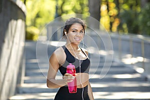 Attractive sporty black girl with bottle of water at park