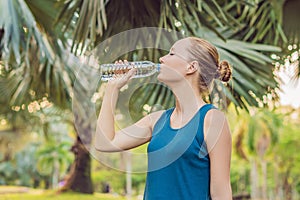 Attractive sporty woman drinking water from a bottle after jogging or running