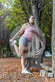 Attractive sporty woman warming up in a park. girl doing warm-up exercises in a park