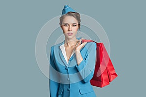 Attractive stewardess holding red shopping bags.