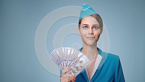 Attractive stewardess in uniform holds US dollars in her hand.