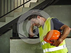. Attractive stressed and frustrated construction worker man in vest and builder helmet looking tired and worried suffering