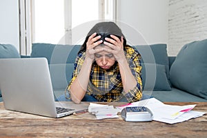 Attractive stressed woman managing finances, reviewing bank accounts, paying bills using laptop