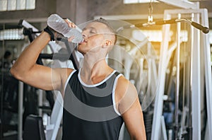 Attractive strong man standing and drinking water in gym,Male break and relex after workout,Healthcare concept