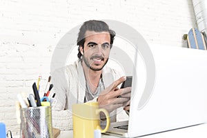 Attractive student or hipster style freelancer businessman working with laptop computer and mobile phone