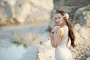 Attractive stunning woman with long hair in a long pastel dress with a bare back turns to the camera with fluttering hair and