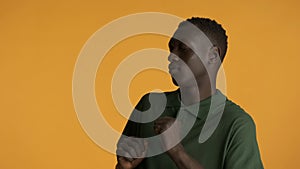 Attractive African American guy closing eyes feeling music while dancing isolated on yellow background