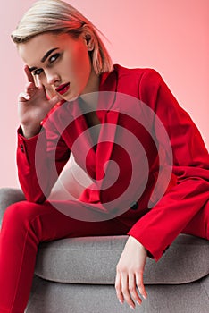 attractive stylish elegant woman in red clothes posing in armchair,