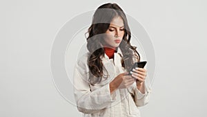 Attractive stylish girl intently using smartphone over white background