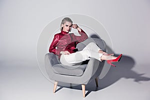 attractive stylish girl posing on armchair for fashion shoot,