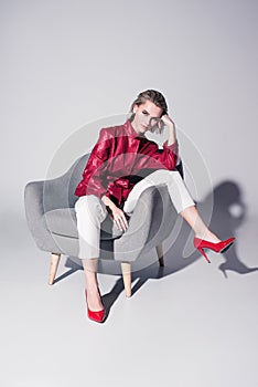 attractive stylish girl posing on armchair for fashion shoot,