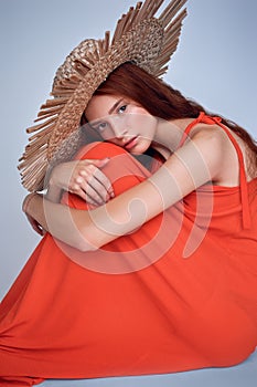 attractive stylish girl posing in red dress and straw hat