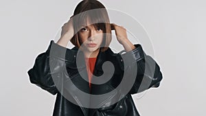 Attractive stylish girl preening her haircut confidently looking in camera over white background