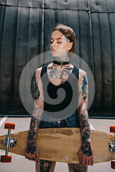 attractive stylish tattooed girl with closed eyes holding