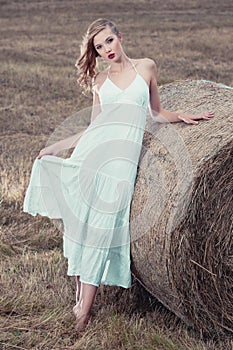 Attractive stylish Woman in long white summe dress near hay bal photo