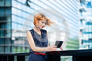 Attractive stylish woman standing watching media on her tablet