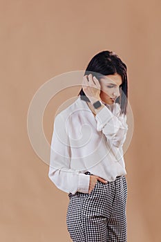 Attractive stylish young girl in business attire posing on cream background. concept of stylish clothes and sophistication