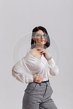 Attractive stylish young girl in business clothes posing on light background in studio. concept of stylish clothes and