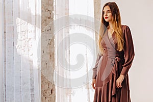 Attractive stylish young girl near the window in light interior