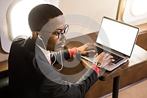 Attractive and successful African American businessman with glasses working on a laptop while sitting in the chair of