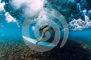 Attractive surfer woman dive under crashing barrel wave