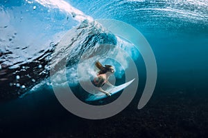 Attractive surfer woman dive underwater, under barrel wave in blue ocean