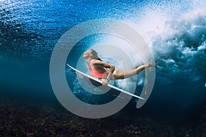 Attractive surfer woman dive underwater with under wave.