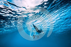 Attractive surfer woman dive underwater with under wave in ocean