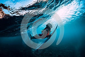 Attractive surfer woman dive underwater with under wave and sun light