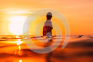 Attractive surfer woman on a surfboard in ocean. Surfgirl at sunset