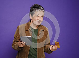 Attractive surprised woman using digital tablet for online shopping with a credit card isolated studio
