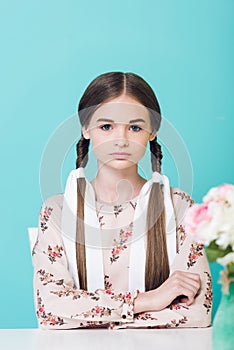 attractive teen girl with braids sitting at table with flowers