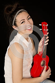 Attractive teen girl holding a red ukulele smiling