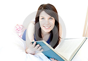 Attractive teen girl studying lying on a bed