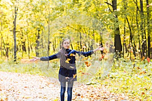 Attractive teen girl throwing leaves in the air