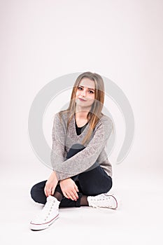 Attractive teenage girl sitting on the floor on white background.