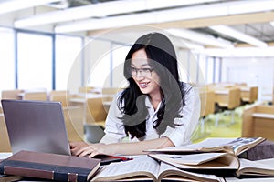 Attractive teenage schoolgirl typing on laptop