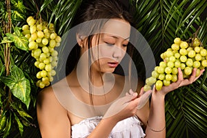 Attractive teenager girl holding grapes in hands