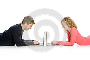 Attractive teenagers lying down using lap tops