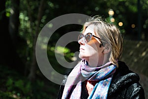 Attractive thirty year old woman posing in the sun, in a Brussels citypark during spring
