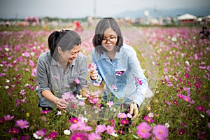 Attractive trendy mum and daughter selecting flowers at open park.