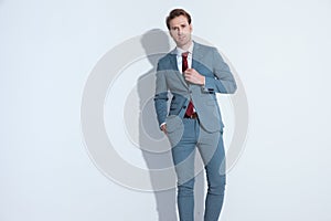 Attractive unshaved businessman in blue suit fixing tie