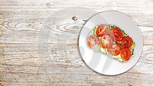 Attractive vegan sandwich with avocado, cherry tomatoes and cheese cream, on wooden background