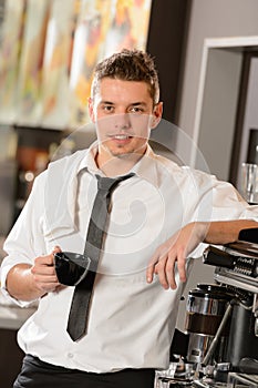 Attractive waiter leaning on espresso machine
