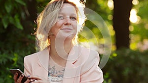 Attractive white woman blonde using a smartphone in park at sunny day