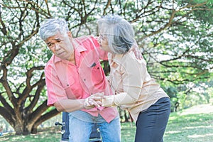 attractive wife helping husband to get up from the wheelchair to do physical therapy with learning to walk